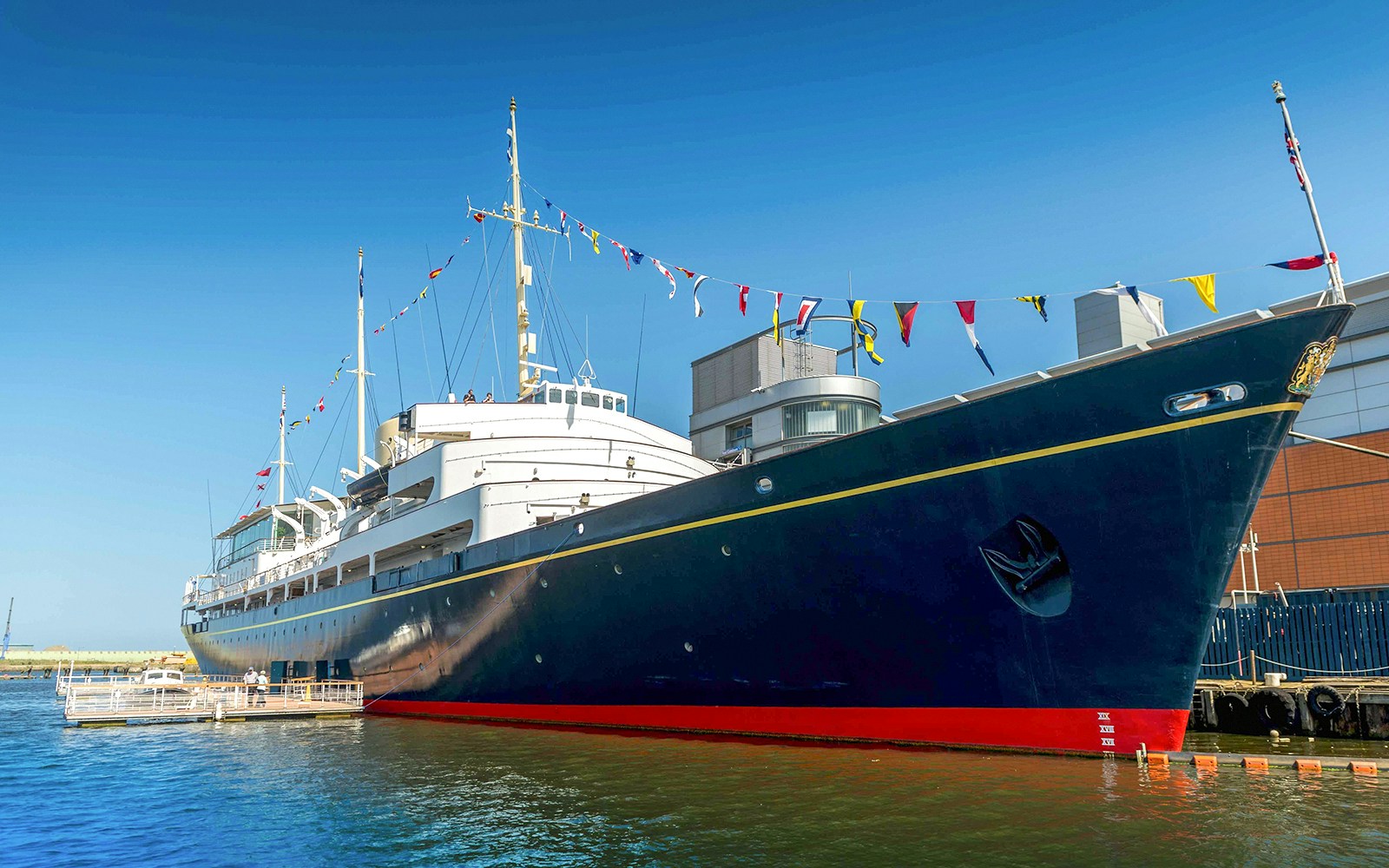 Royal Yacht Britannia docked in Edinburgh with colorful flags.