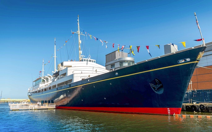 Royal Yacht Britannia docked in Edinburgh with colorful flags.