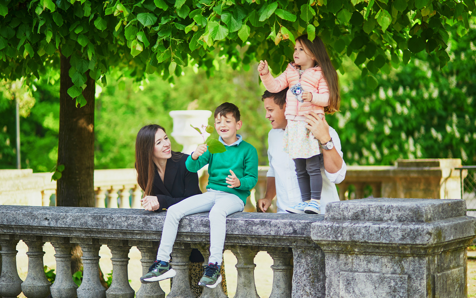 Family relaxing in Tuileries Garden, Paris with children playing near fountain.
