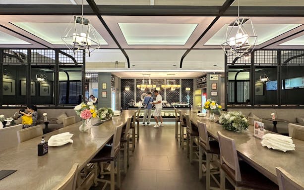 Coral International Lounge dining area at Phuket International Airport with guests and floral decor.