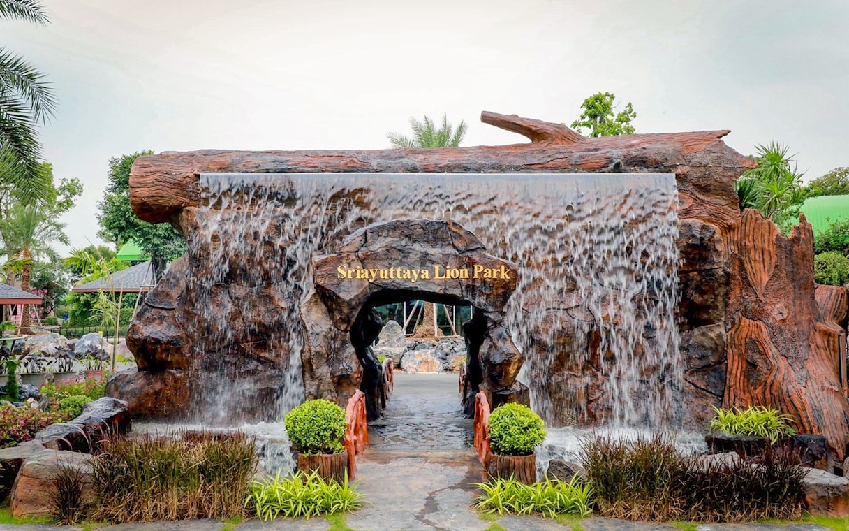 Entrance of Sri Ayutthaya Lion Park with waterfall feature and greenery.