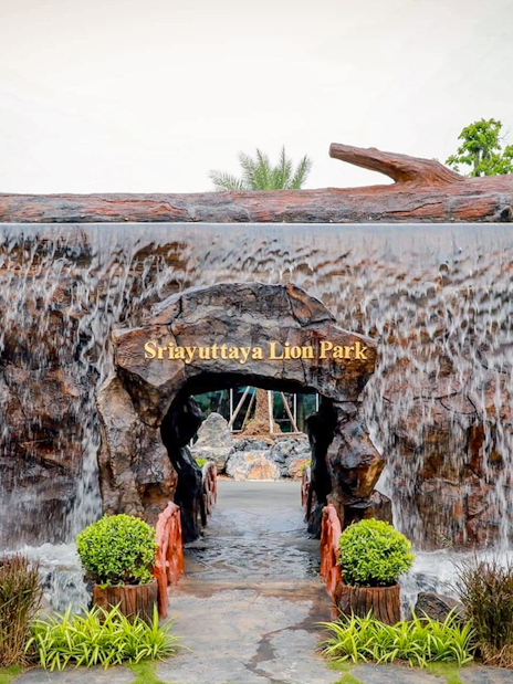 Entrance of Sri Ayutthaya Lion Park with waterfall feature and greenery.