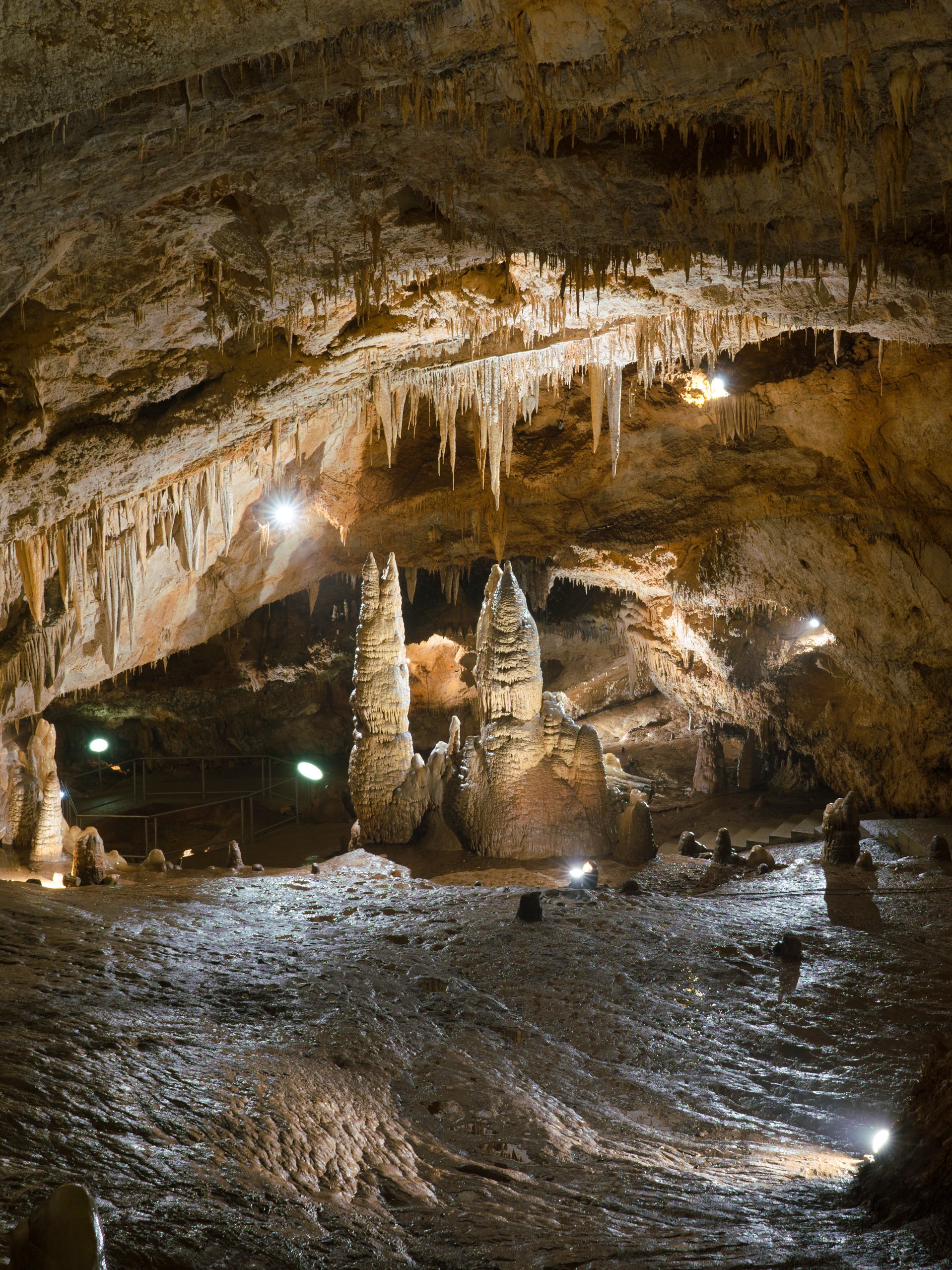 Stalactites and stalagmites inside Lipa Cave, Montenegro, with illuminated rock formations.