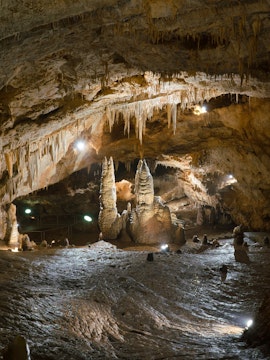 Stalactites and stalagmites inside Lipa Cave, Montenegro, with illuminated rock formations.