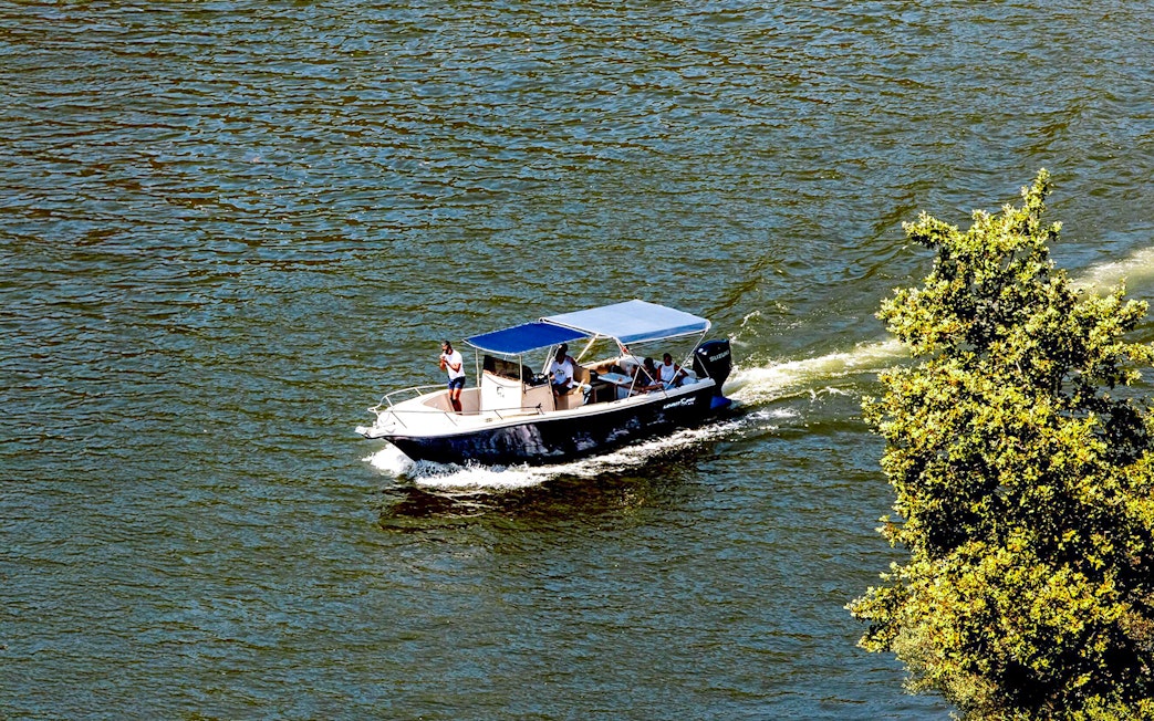Boat cruising on Douro River in the evening with passengers enjoying the view.