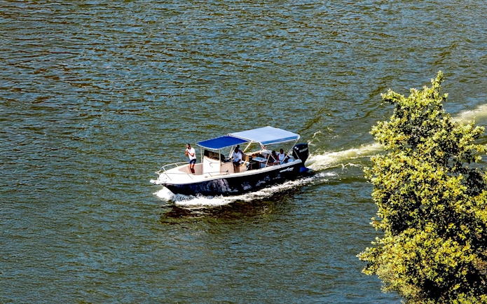 Boat cruising on Douro River in the evening with passengers enjoying the view.