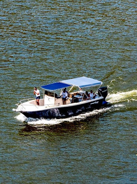 Boat cruising on Douro River in the evening with passengers enjoying the view.