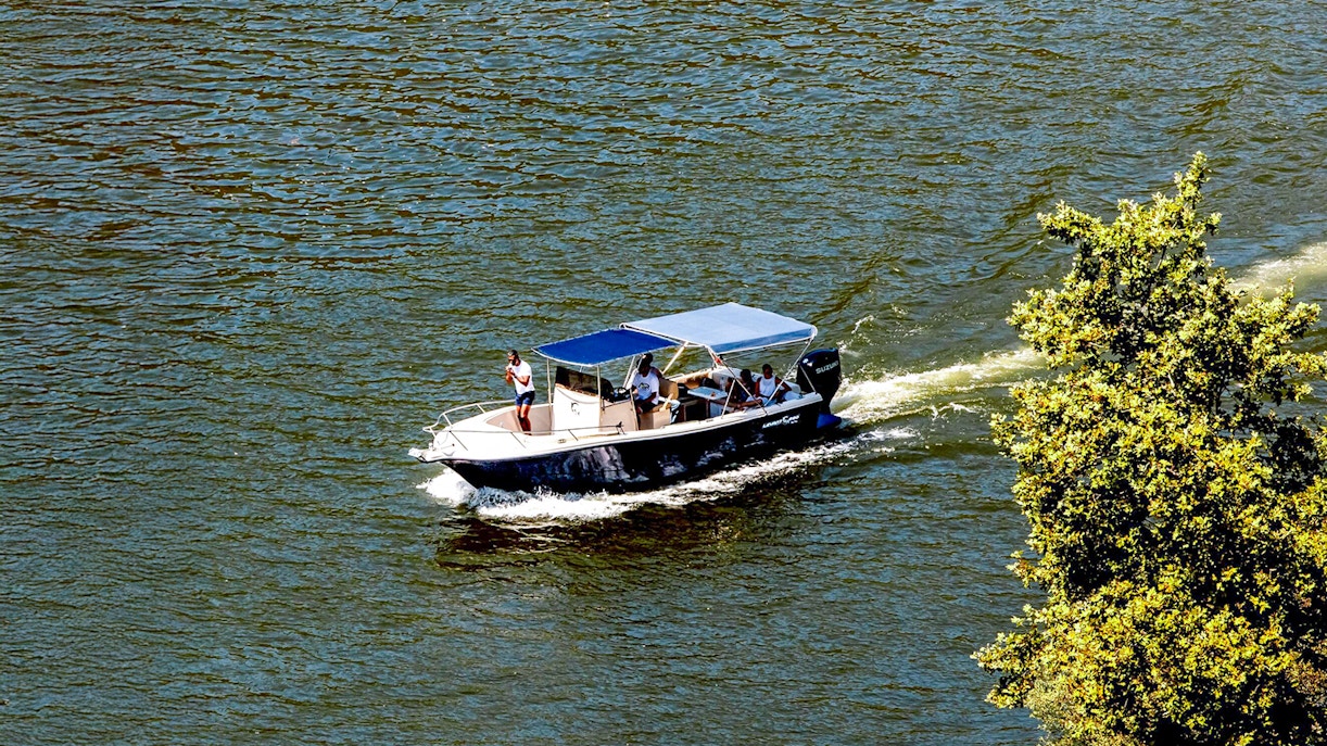 Boat cruising on Douro River in the evening with passengers enjoying the view.