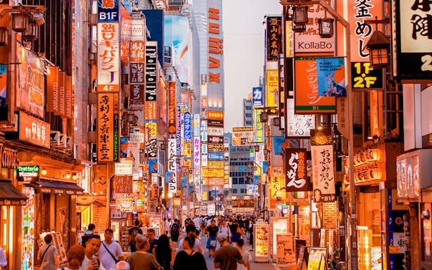 Bustling street in Tokyo, Japan, with vibrant neon signs and crowds, ideal for 3G Tourist eSIM use.