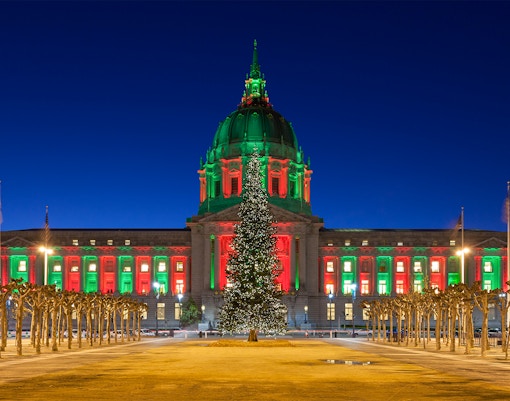 San Francisco City Hall illuminated with Christmas lights at night.