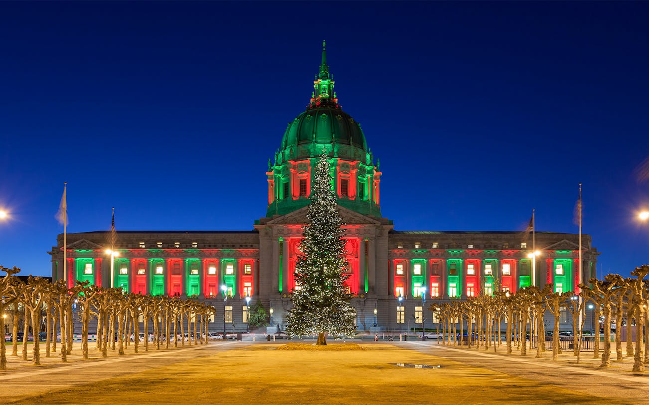 San Francisco City Hall illuminated with Christmas lights at night.
