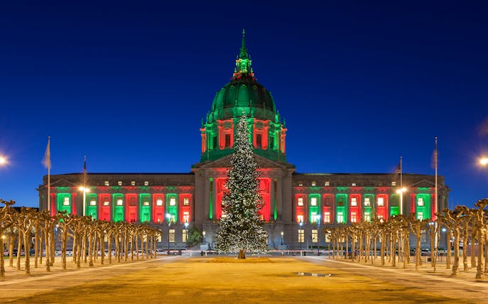 San Francisco City Hall illuminated with Christmas lights at night.