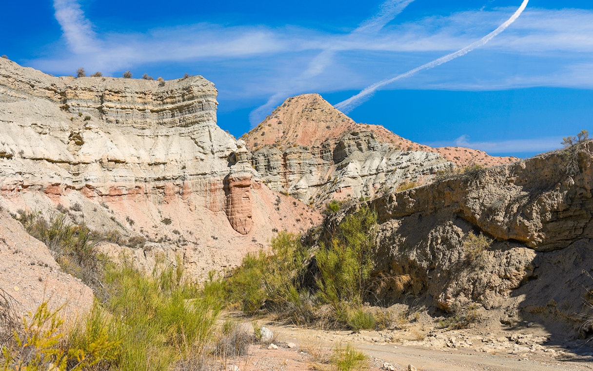 Granada Geopark desert landscape with layered rock formations under a clear blue sky.