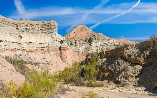 Granada Geopark desert landscape with layered rock formations under a clear blue sky.