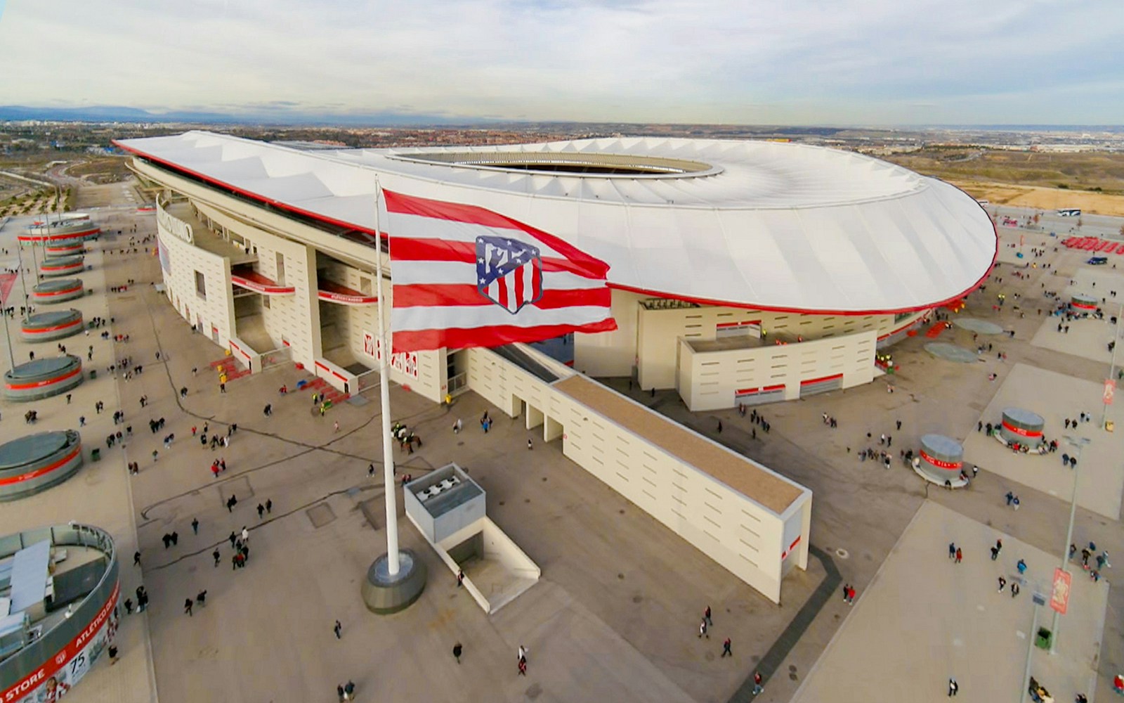 Aerial view of Atlético de Madrid Stadium with surrounding plaza and flag.