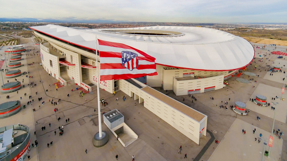 Aerial view of Atlético de Madrid Stadium with surrounding plaza and flag.