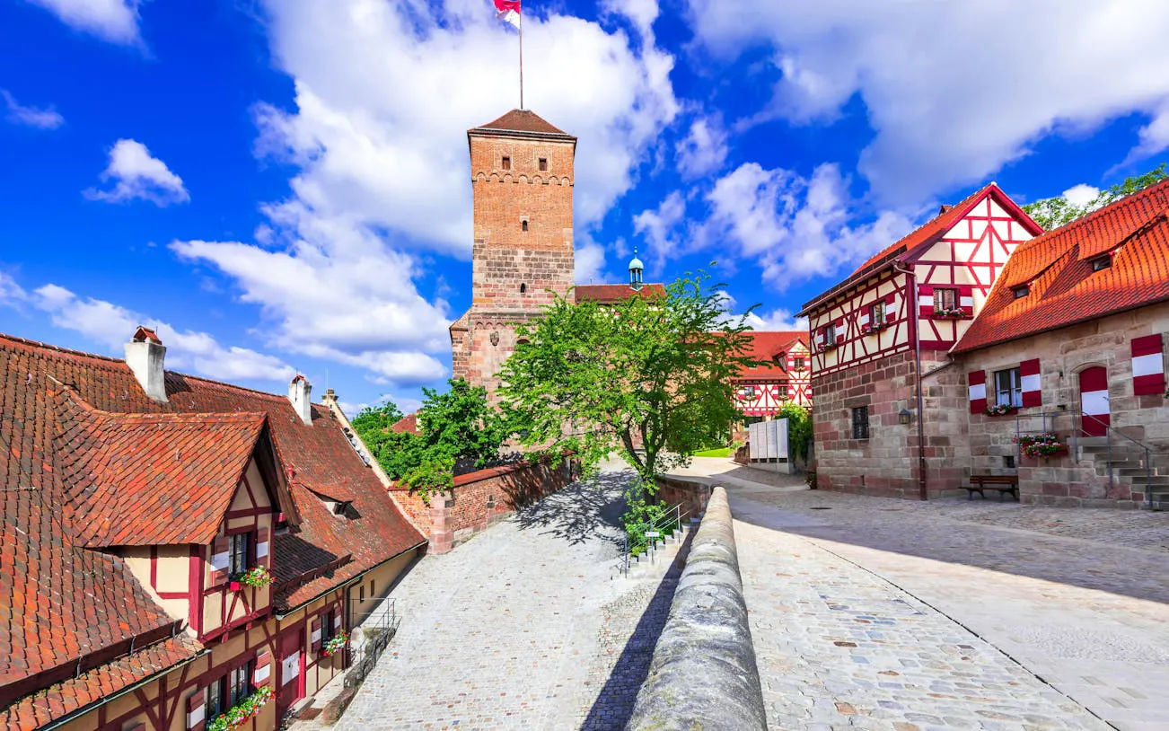 Nuremberg castle tower and half-timbered houses on a cobblestone street.