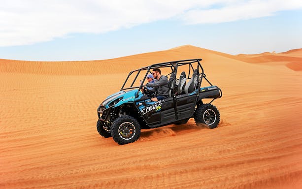 Dune buggy driving through Dubai desert sand dunes.