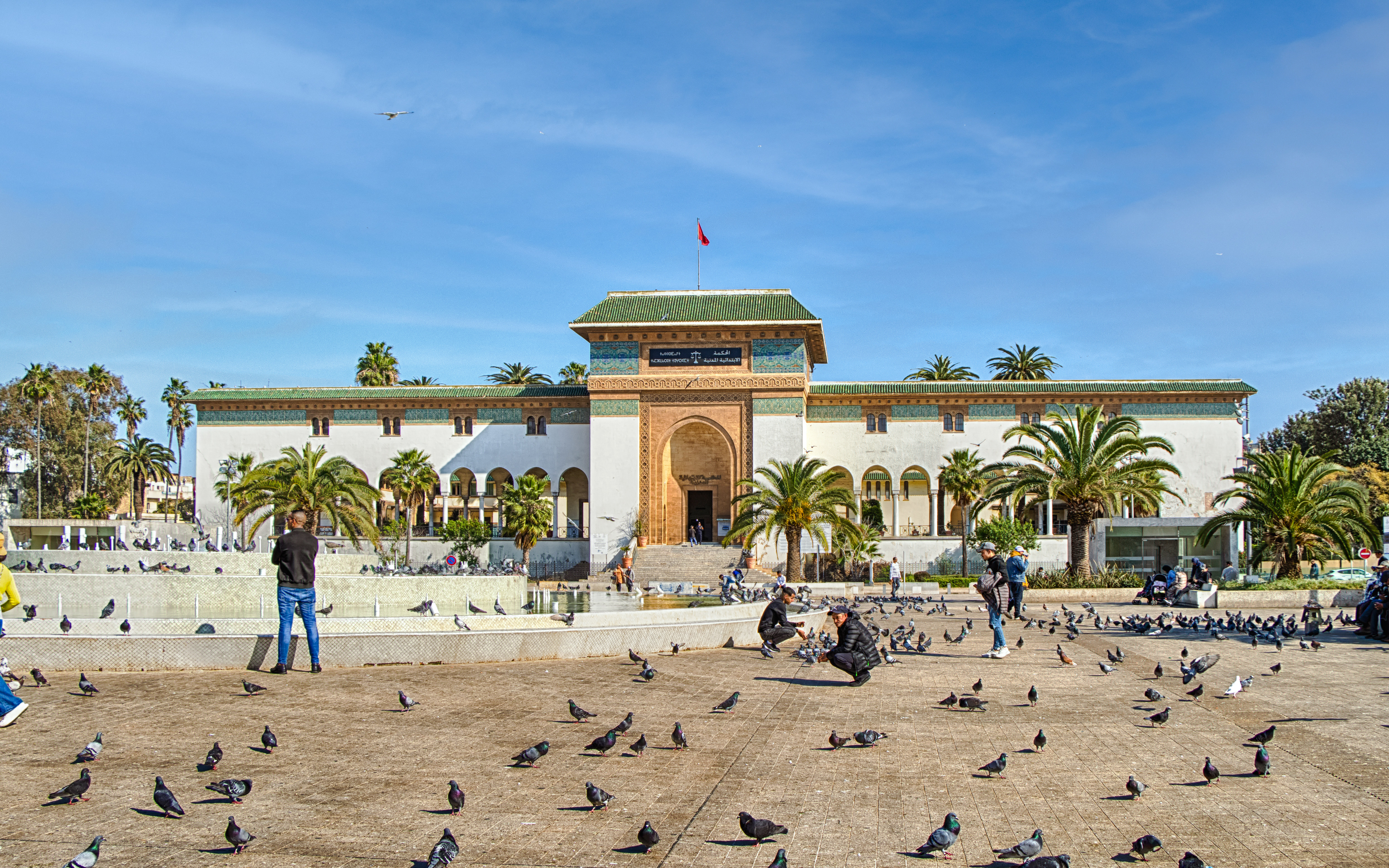 Palace of Justice on Mohammed V Square, Casablanca, with people and pigeons in the foreground.