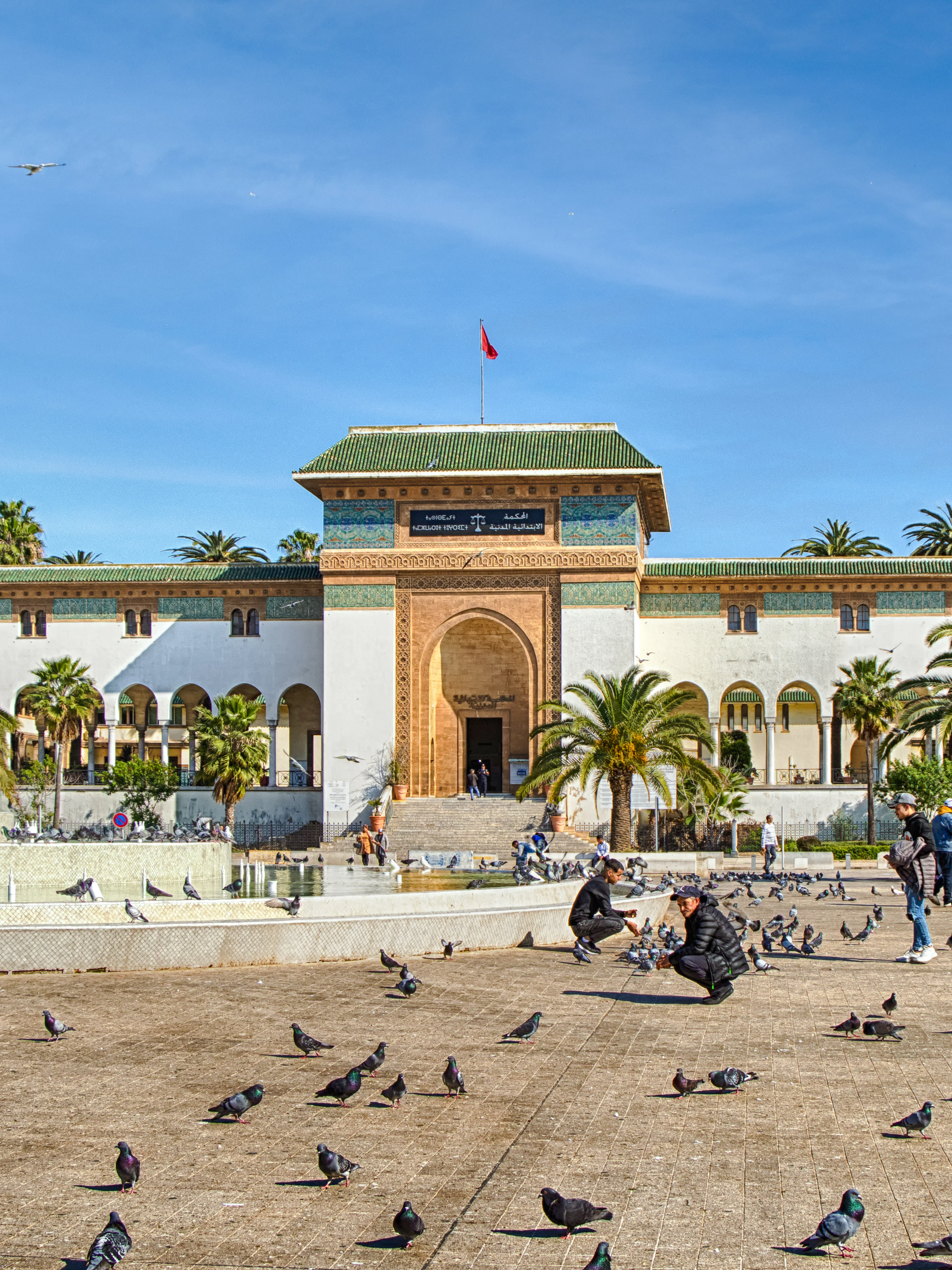 Palace of Justice on Mohammed V Square, Casablanca, with people and pigeons in the foreground.