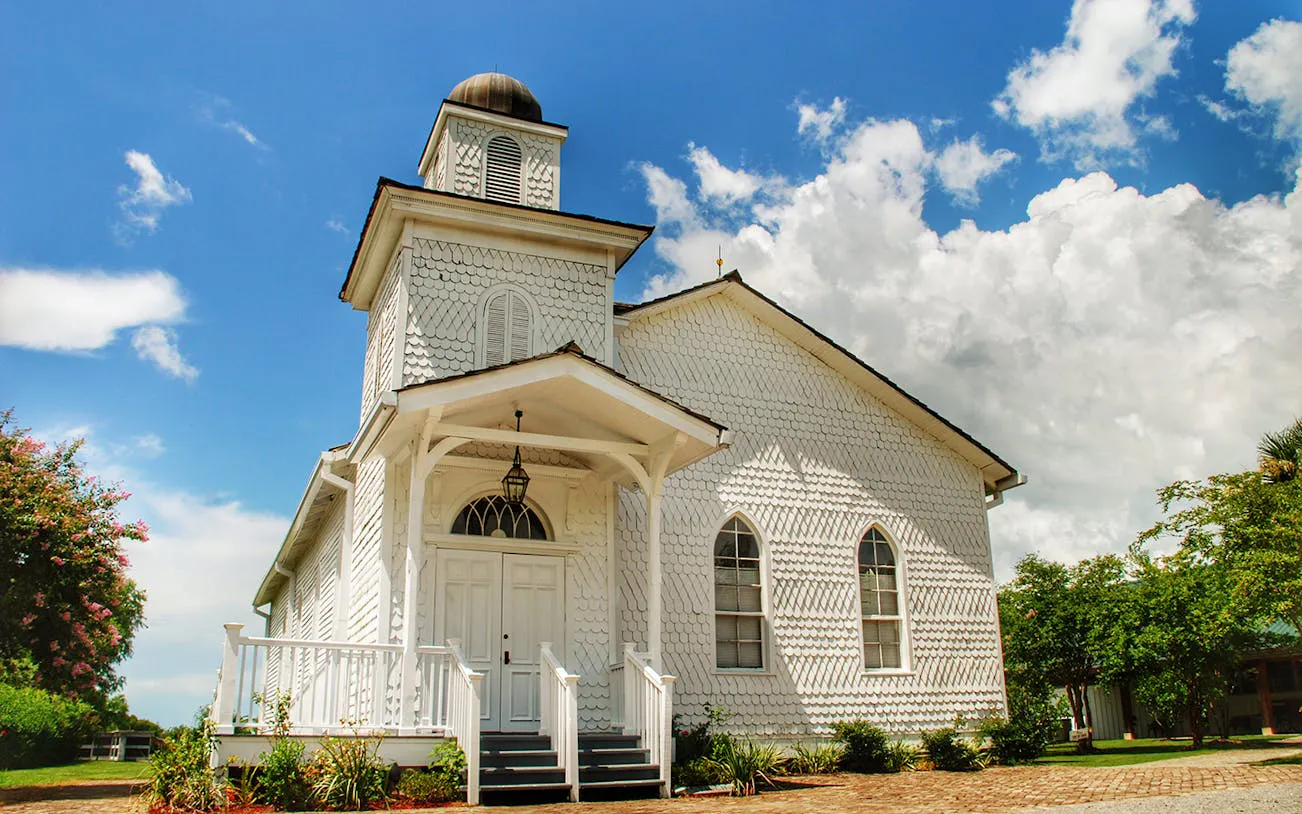 Whitney Plantation chapel with white facade under blue sky, New Orleans tour.