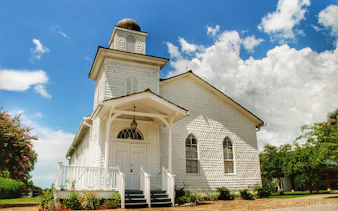 Whitney Plantation chapel with white facade under blue sky, New Orleans tour.