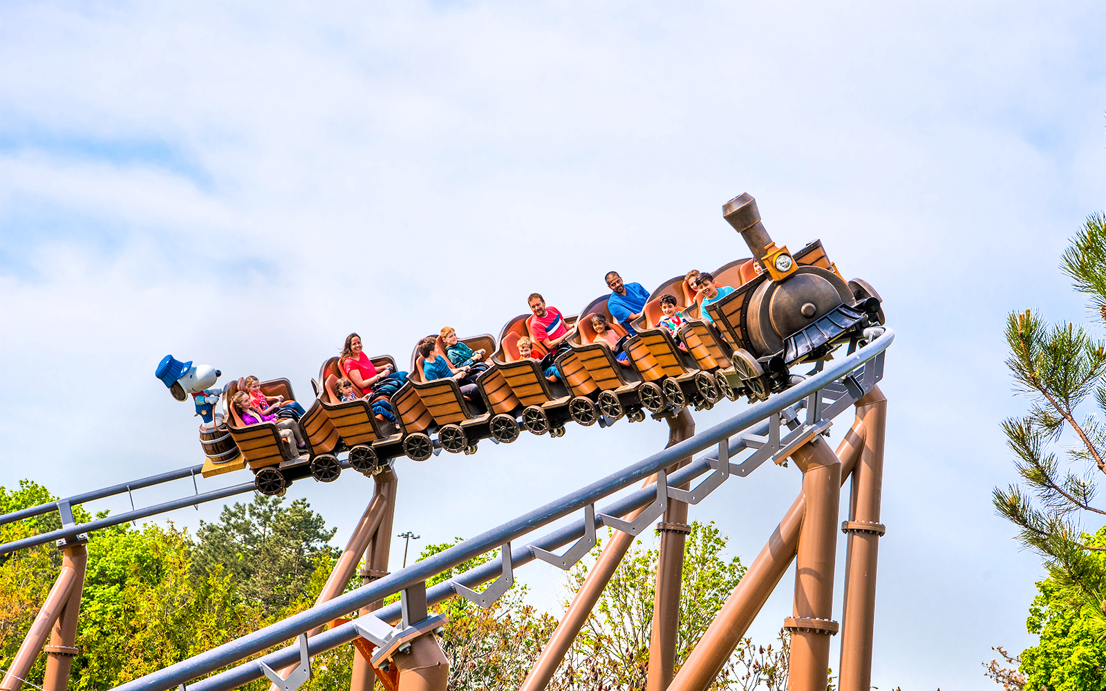 Families riding SNOOPY'S® Racing Railway roller coaster at Six Flags Carowinds.