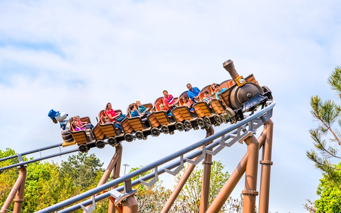 Families riding SNOOPY'S® Racing Railway roller coaster at Six Flags Carowinds.
