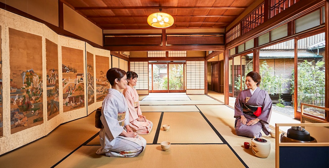 Women in kimonos participating in a Maikoya tea ceremony in a traditional Japanese room.