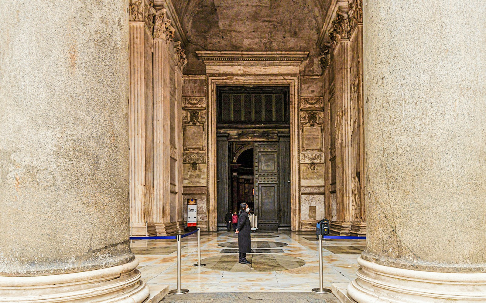 Pantheon entrance with bronze door in Rome, framed by large columns.