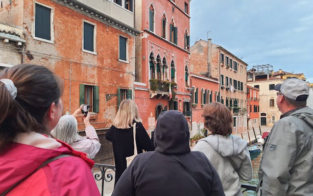 Tourists exploring historic Venetian buildings on a street food and sightseeing tour in Venice.