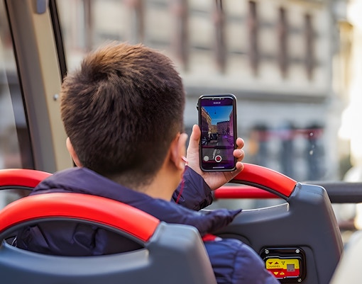 Passenger photographing Copenhagen landmarks from hop-on hop-off tour bus.