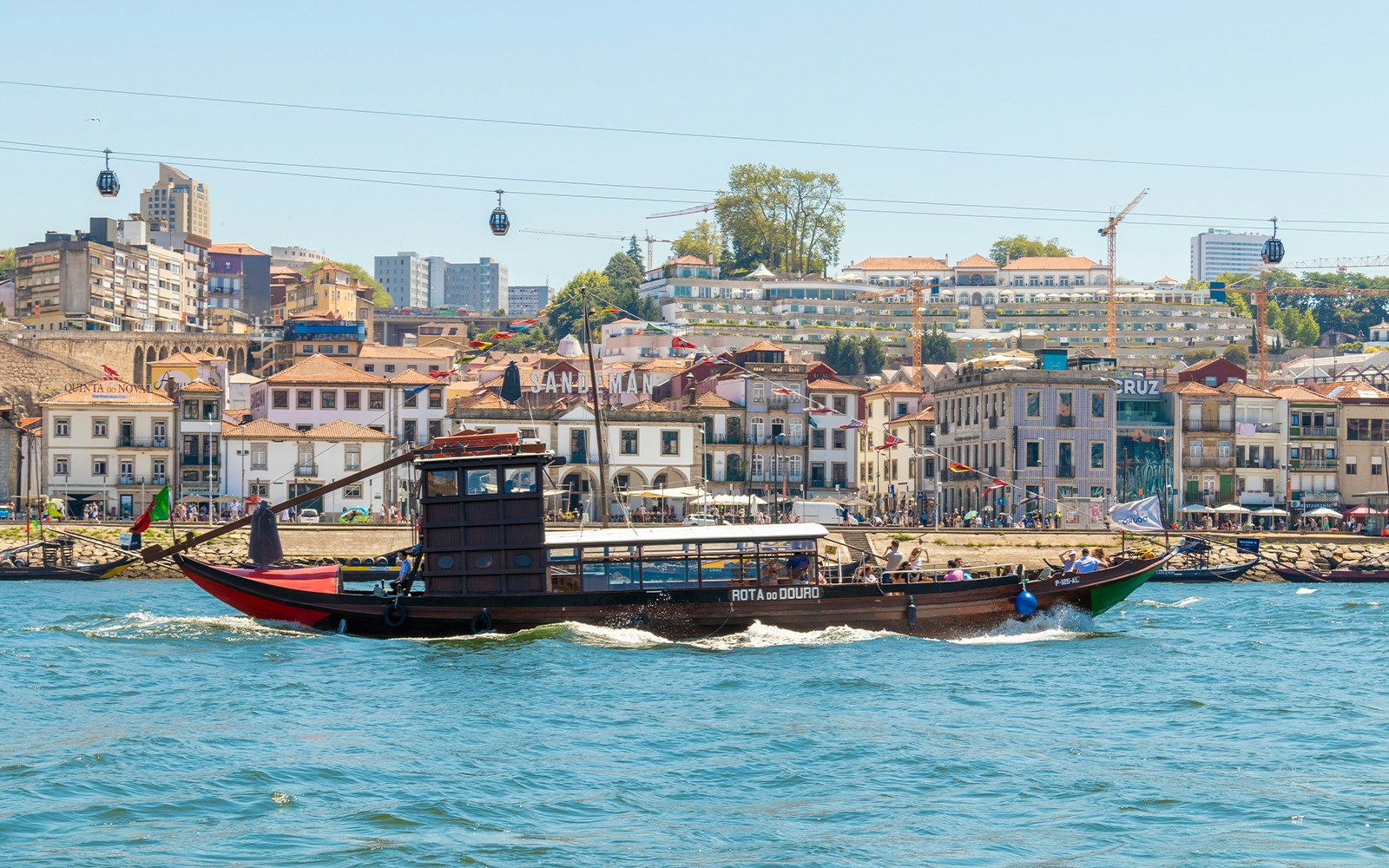 Tourist boat cruising on the Douro River with Porto cityscape in the background.