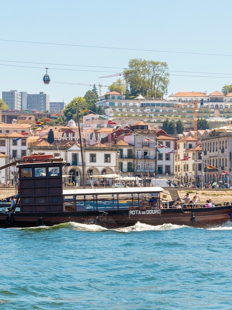 Tourist boat cruising on the Douro River with Porto cityscape in the background.