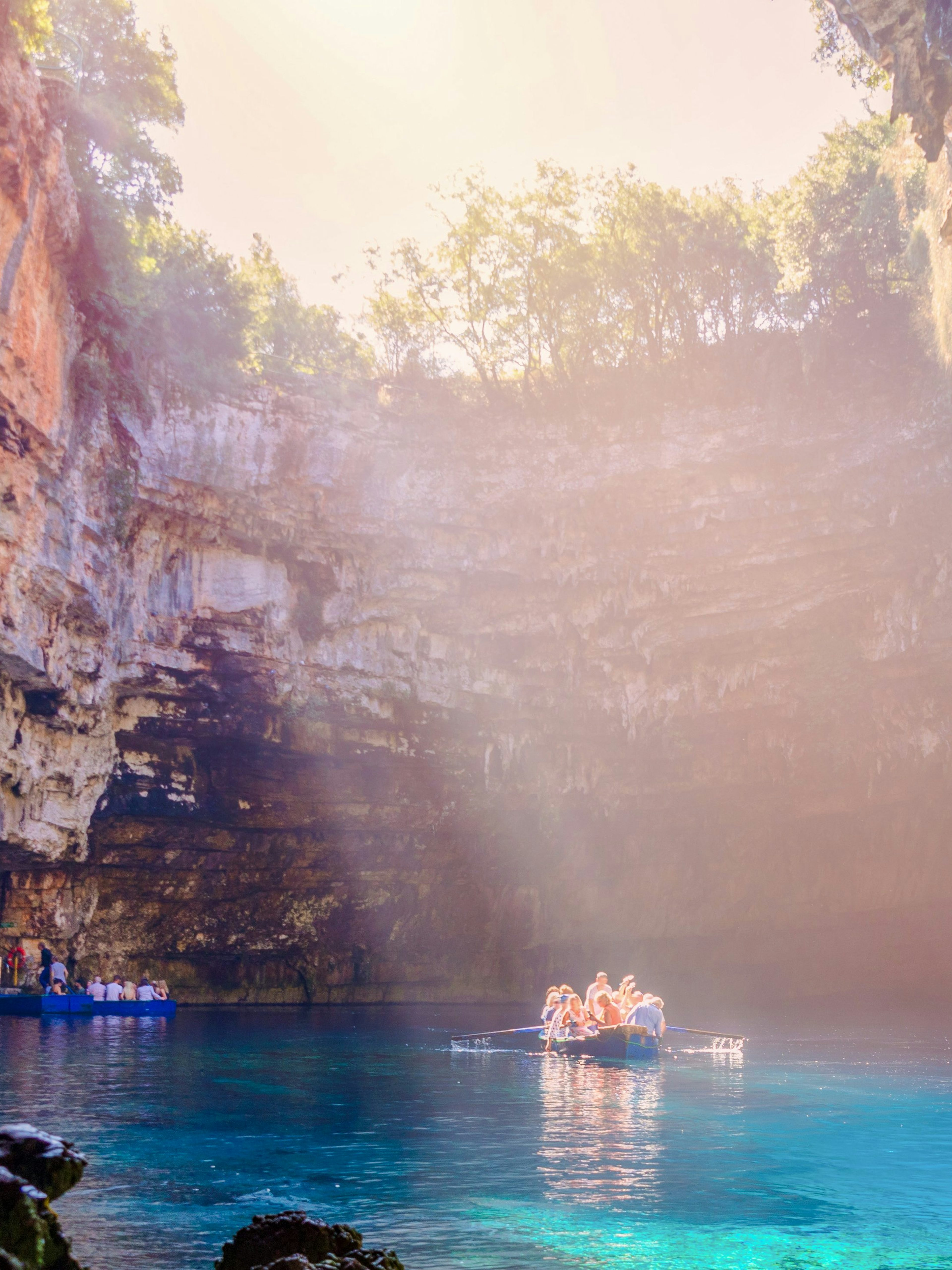 Boat tour inside Melissani Cave on Kefalonia Island, Greece, with sunlight illuminating the turquoise water.
