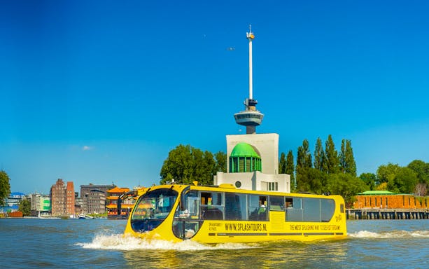 Yellow amphibious bus sailing near the Euromast in Rotterdam.
