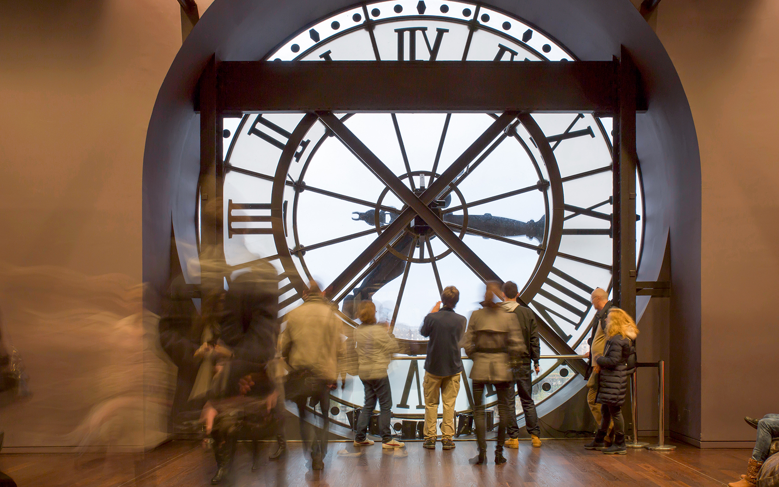 Tourists viewing Paris through the large clock at Musée d'Orsay during a guided tour.