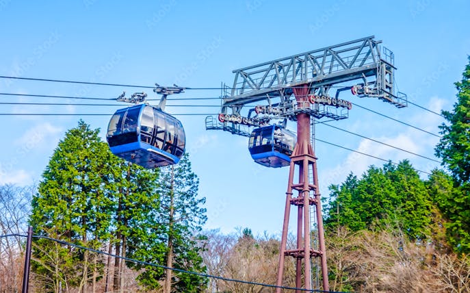 Hakone Komagatake Ropeway gondolas against a backdrop of trees and blue sky.
