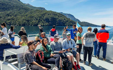 Travelers on a sightseeing boat deck in Patagonia with scenic mountain views.