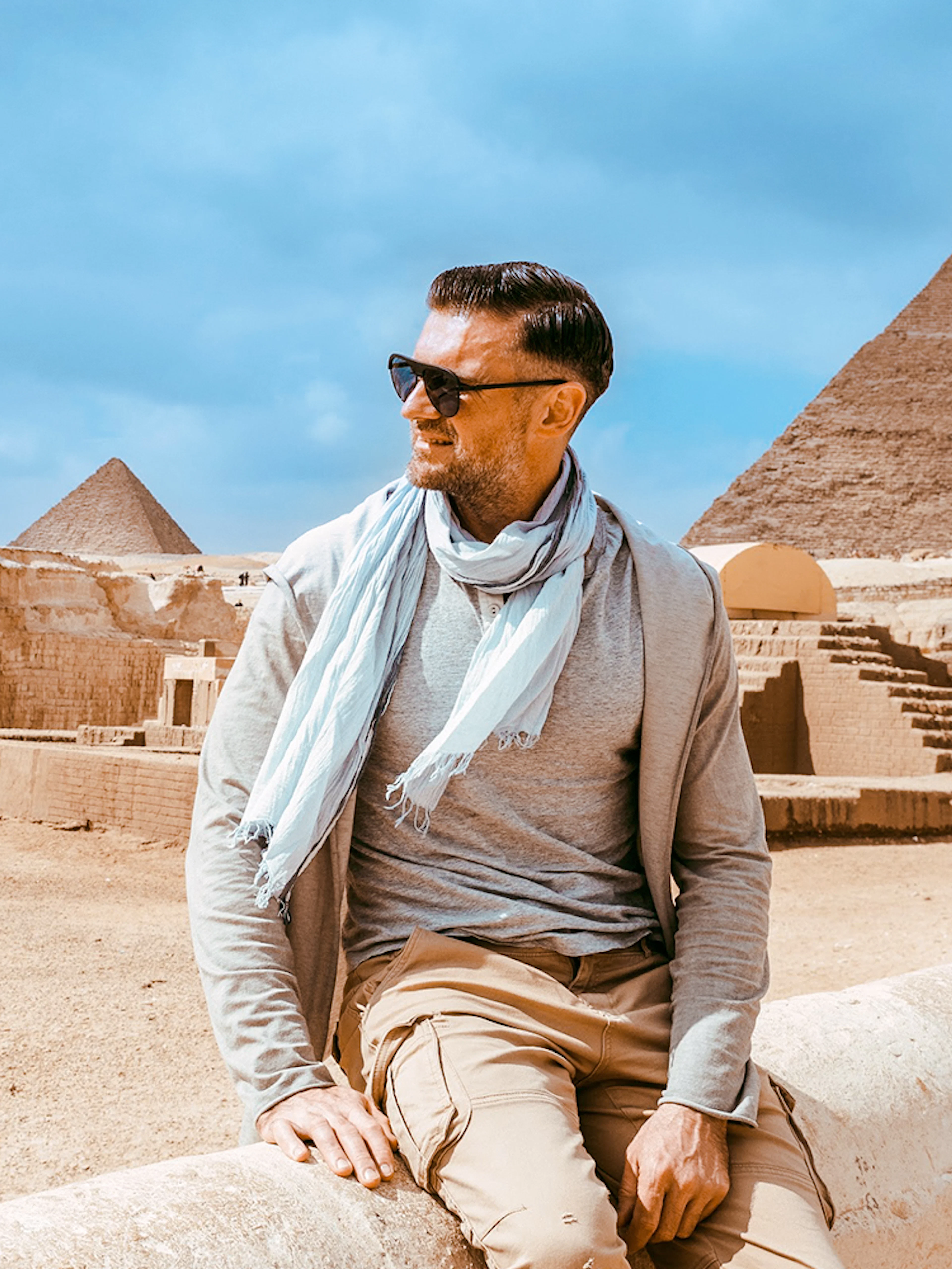 Tourist sitting near the Sphinx with Pyramid of Giza in the background.