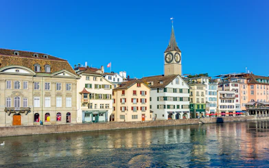 Historic buildings along the Limmat River with St. Peter's Church in Zürich.