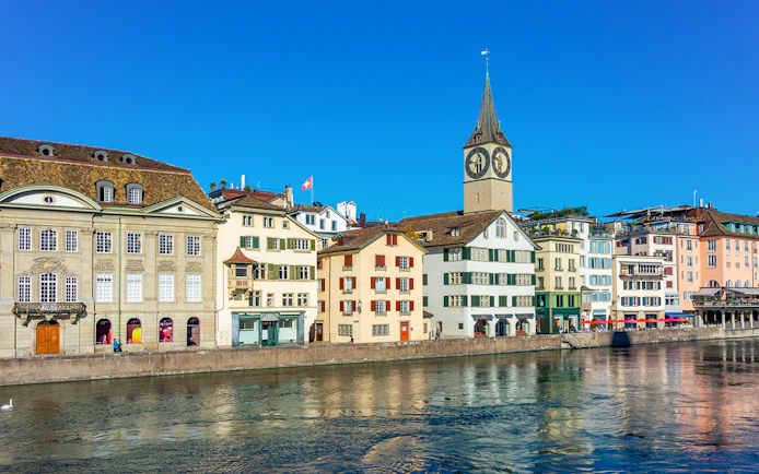 Historic buildings along the Limmat River with St. Peter's Church in Zürich.