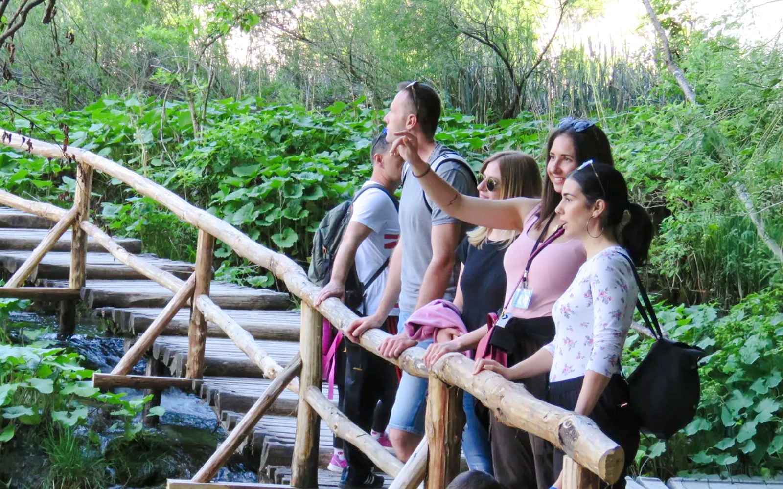 Tourists with a guide on a wooden path at Plitvice Lakes National Park.