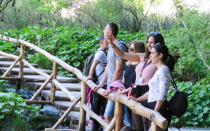 Tourists with a guide on a wooden path at Plitvice Lakes National Park.
