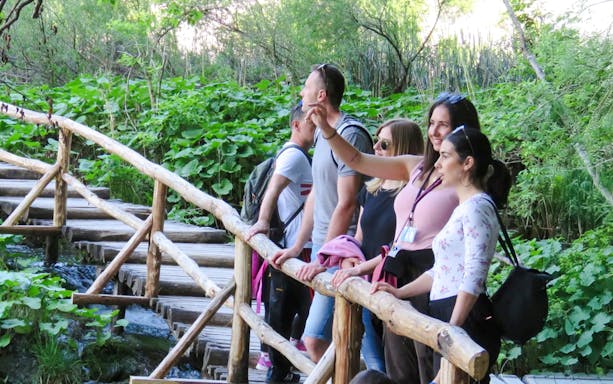 Tourists with a guide on a wooden path at Plitvice Lakes National Park.