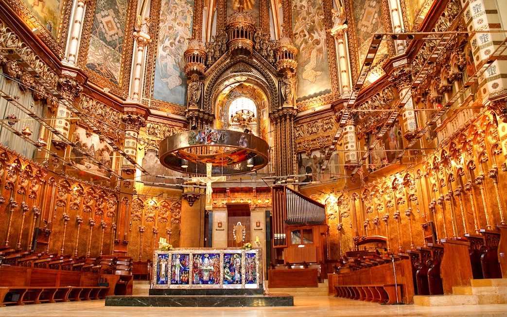 Basilica interior at Montserrat Monastery, featuring ornate altar and detailed frescoes.