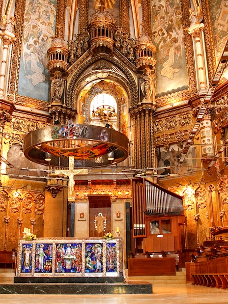 Basilica interior at Montserrat Monastery, featuring ornate altar and detailed frescoes.