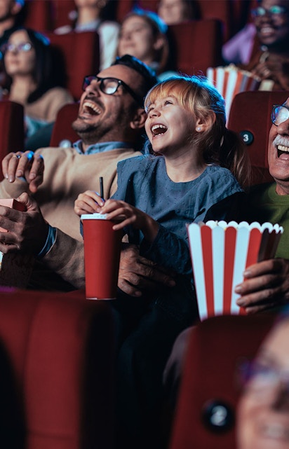 Audience enjoying a movie in a theater with popcorn and drinks.