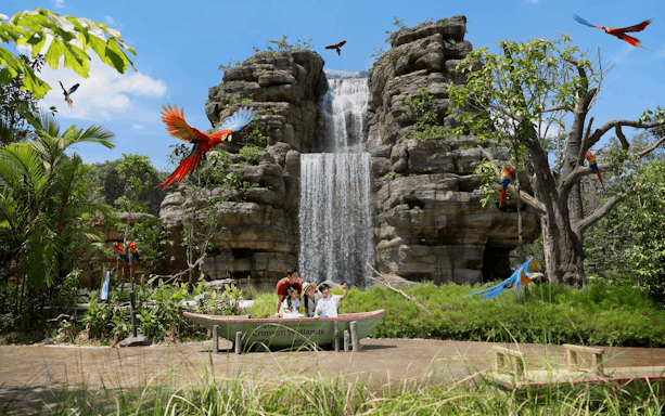 Family enjoying a boat ride at Hong Leong Foundation Crimson Wetlands with waterfall and colorful parrots.
