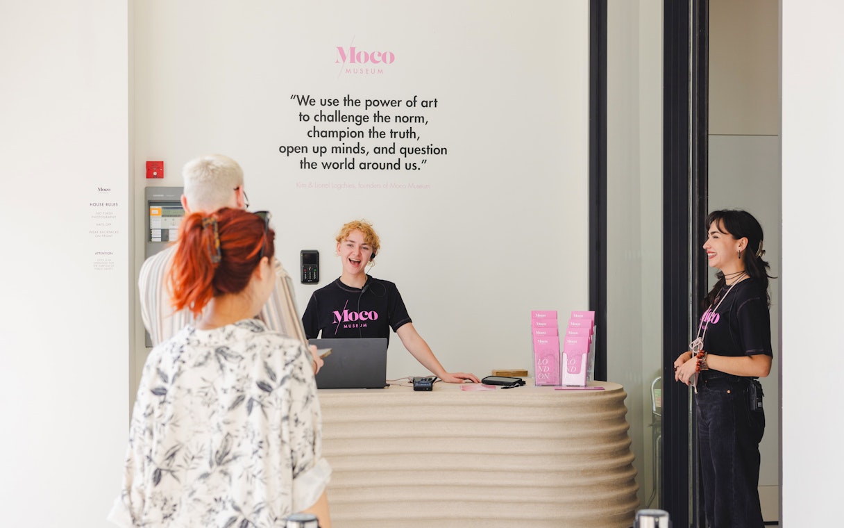 Reception area of Moco Museum London with staff assisting visitors.